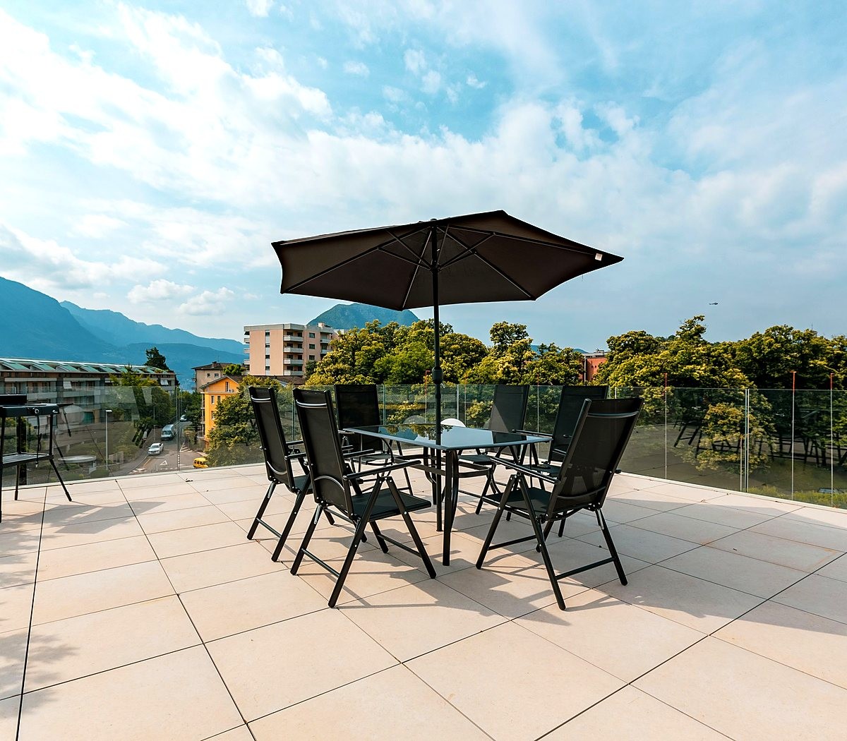 Terraço do condomínio com mesa, cadeiras e vista para as montanhas